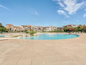 a swimming pool in a resort with buildings in the background at Apartment Les Marines-28 by Interhome in La Foux