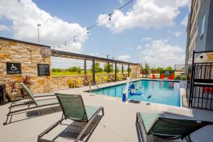 einen Pool mit Stühlen und ein Gebäude in der Unterkunft Tru by Hilton Pflugerville, TX in Pflugerville