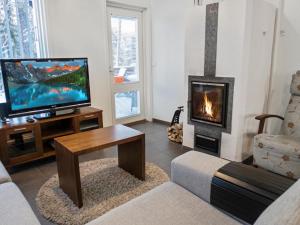 a living room with a television and a fireplace at Holiday Home Vuokatinlampi 7 a - 2 ski passes incl- in by Interhome in Lahdenperä