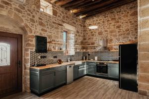 a kitchen with gray cabinets and a brick wall at La casa dell'arch in Haraki