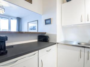 a kitchen with white cabinets and a black counter top at Apartment Les Marinas-3 by Interhome in Deauville
