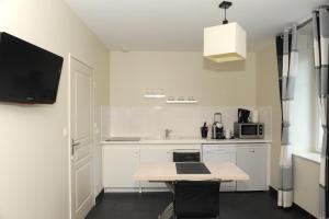 a white kitchen with a table and a tv on the wall at Aux Jardins de L'Isle in Vienne