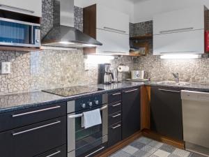 a kitchen with black and white cabinets and a sink at Holiday Home Vuokatinlampi 7 a - 2 ski passes incl- in by Interhome in Lahdenperä +15 photos