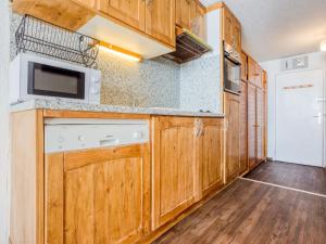 a kitchen with wooden cabinets and a white dishwasher at Apartment Les Grandes Platières-22 by Interhome in Tignes