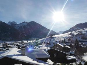 a village covered in snow with the sun in the background at Apartment Kristall by Interhome in Zweisimmen