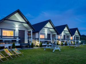 a row of houses with picnic tables in the grass at Domki Malibu in Rusinowo