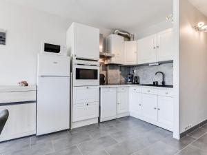a white kitchen with white cabinets and appliances at Apartment Les Marinas de la Plage I-3 by Interhome in Le Grau-du-Roi