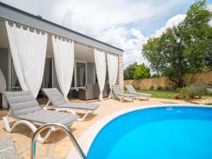 a swimming pool with chairs and a house at Holiday Home Ofelia by Interhome in Buroli