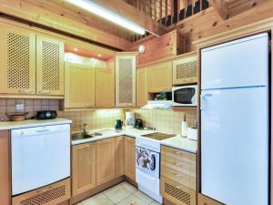 een keuken met houten kasten en een witte koelkast bij Holiday Home Saunaharju 3 by Interhome in Kolinkylä