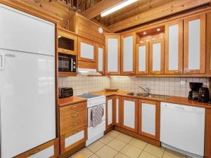 eine Küche mit Holzschränken und einem weißen Kühlschrank in der Unterkunft Holiday Home Saunaharju 4 by Interhome in Kolinkylä + 19 Fotos