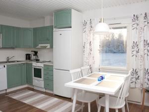 a kitchen with green cabinets and a white refrigerator at Holiday Home Metsätähti by Interhome in Vuokatti