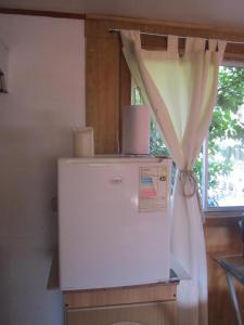 a white refrigerator in a kitchen with a window at Cabaña Cerezo in Guayacán