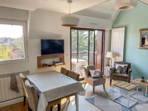 a living room with a table and chairs and a tv at Apartment Le Fairway-5 by Interhome in Deauville