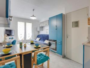 a kitchen with blue cabinets and a table and chairs at Apartment Les Jardins de l'Océan-41 by Interhome in Pontaillac