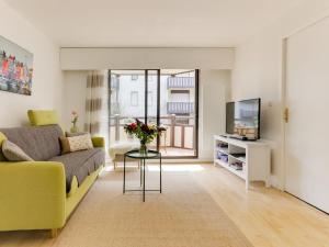 a living room with a yellow couch and a tv at Apartment Le Fairway-6 by Interhome in Deauville