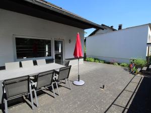a patio with a table and chairs and a red umbrella at Apartment Eifelnatur - Haus 3-2 by Interhome in Immerath