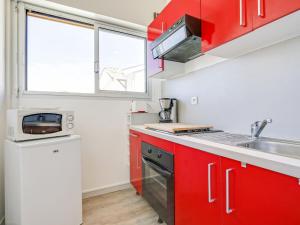 een keuken met rode kasten en een wastafel bij Studio La Passerelle by Interhome in Gujan-Mestras