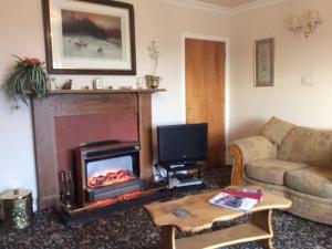 a living room with a fireplace and a couch at Holiday Home Wester Riechip by Interhome in Dunkeld