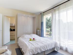 een slaapkamer met een wit bed en een groot raam bij Studio Les Prairies by Interhome in Deauville