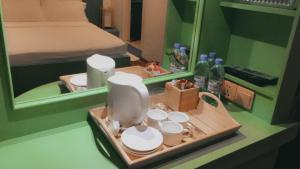 eine Theke mit einem Tablett mit Tassen und einem Spiegel in der Unterkunft Niu Inn & Spa in Hulhumale