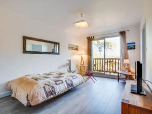 a bedroom with a bed and a television and a balcony at Apartment Résidence Le Parc by Interhome in Arcachon