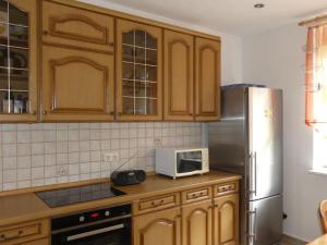 a kitchen with wooden cabinets and a stainless steel refrigerator at Holiday Home Landhaus Inselsee by Interhome in Mühl Rosin