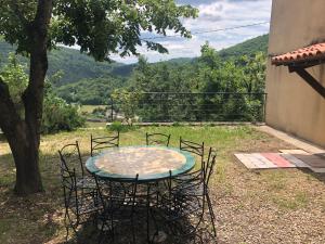 una mesa y sillas con vistas a un árbol en Gîte La Maison de Huguette et Lucien, en Le Vigan