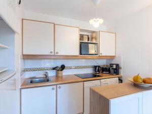 a kitchen with white cabinets and a sink at Apartment Domaine de Clairefontaine-3 by Interhome in Deauville +17 photos