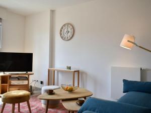 uma sala de estar com um sofá azul e um relógio na parede em Apartment Les Arts-1 by Interhome em Deauville