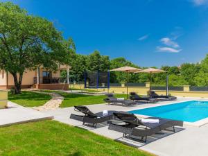 a pool with chairs and umbrellas in a yard at Holiday Home Villa Aniva by Interhome in Žminj