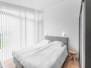 a white bedroom with a bed and a window at Holiday Home Ruisweg 55 by Interhome in Wemeldinge
