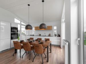 a kitchen and dining room with a wooden table and chairs at Holiday Home Ruisweg 55 by Interhome in Wemeldinge +13 photos