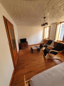 a living room with a bed and chairs and a tv at Gite des luthiers in Mirecourt