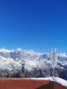 a glass of wine sitting on top of a roof with snow covered mountains at La Tania 309 Le Britania in Courchevel