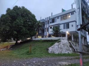 un grand bâtiment blanc avec un arbre à côté dans l'établissement Las Bioma's Aqua-Park, à Villa Tunari