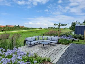 a couch sitting on a wooden deck next to some flowers at Holiday Home Vakantiehuis Ruisweg 83 by Interhome in Wemeldinge
