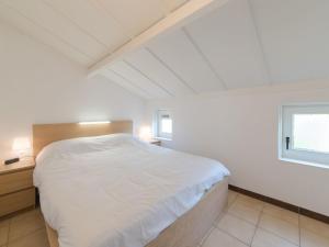 1 dormitorio con cama blanca y ventana en Holiday Home Noordzeepark Zeewind 2-4 by Interhome, en Bredene