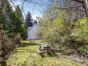 ein altes Haus inmitten eines Gartens mit einem Holztisch in der Unterkunft Holiday Home Russcot by Interhome in Invermoriston