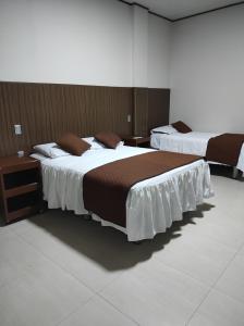 um quarto com 2 camas com lençóis castanhos e brancos em Las Bioma's Aqua-Park em Villa Tunari