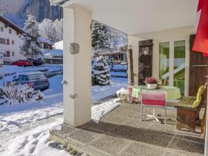 a dog sitting on the porch of a house in the snow at Apartment Chalet im Gässli by Interhome in Lauterbrunnen +18 photos