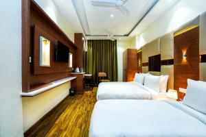 a hotel room with two beds and a television at Hotel Aura Grand By Levelup Hotels in Amritsar