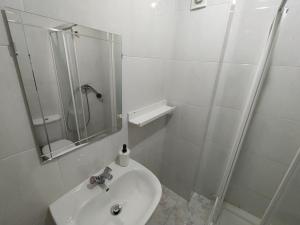 uma casa de banho branca com um lavatório e um chuveiro em AlfandegaPorto Apartments no Porto