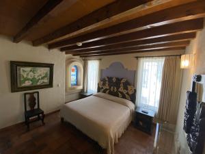 a bedroom with a bed in a room with windows at Casa Árbol Hotel in San Miguel de Allende