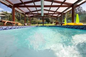 une grande piscine avec une pergola en bois dans l'établissement Casa Compostela, à Bama