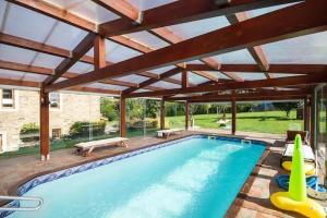 une grande piscine avec une grande pergola en bois dans l'établissement Casa Compostela, à Bama