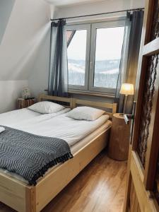 a bedroom with a bed and a large window at Gościniec Odsapka in Murzasichle
