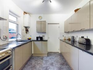 eine Küche mit weißen Schränken und einem Waschbecken in der Unterkunft Cheerful 3 bedroom home with free parking and WIFI in Chester