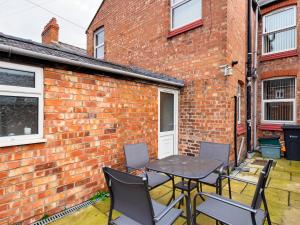 a patio with a table and chairs in front of a brick building at Cheerful 3 bedroom home with free parking and WIFI in Chester