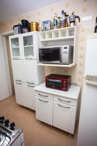 a kitchen with white cabinets and a microwave at Apartamento com Wi-Fi no centro de Guarapari ES in Guarapari