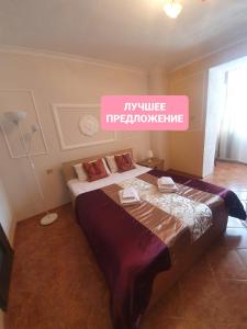 クラスノダールにあるApartamenty Lastochkino Gnezdo-Krasnodar-Center-Stadiumのベッドルーム1室(ピンクの看板が壁に貼られた大型ベッド1台付)